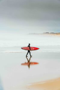 Surfer sur la plage d'Hossegor avec planche rouge